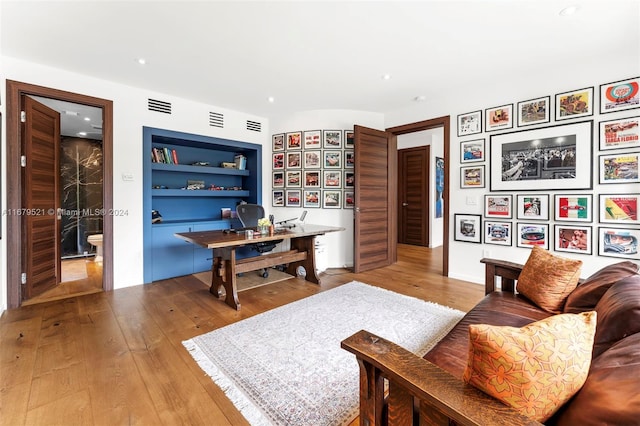 living room with built in features and hardwood / wood-style flooring