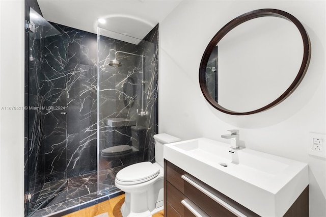 bathroom with tiled shower, vanity, hardwood / wood-style flooring, and toilet