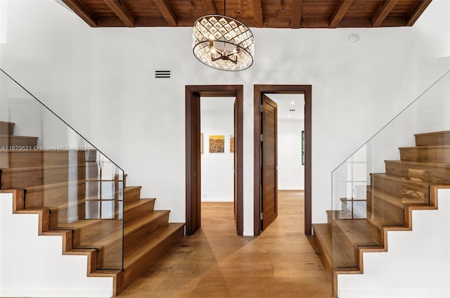 stairs with beamed ceiling, wood-type flooring, a chandelier, and wood ceiling