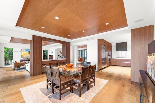 dining room with light hardwood / wood-style floors, a tray ceiling, and wood ceiling