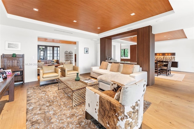 living room featuring light wood-type flooring, a tray ceiling, and wooden ceiling