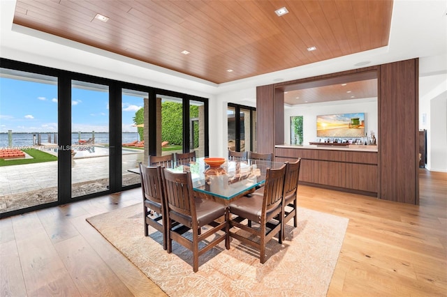 dining area with french doors, light hardwood / wood-style flooring, a tray ceiling, a water view, and wood ceiling