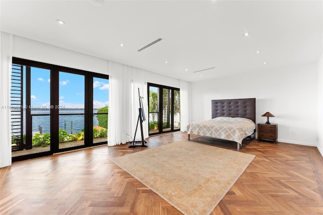 bedroom with access to exterior, a water view, and light parquet flooring