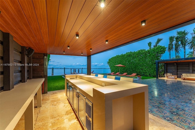 patio terrace at dusk with an outdoor kitchen and a water view