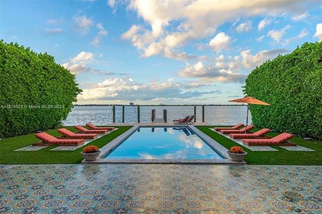 view of swimming pool featuring a water view and a yard