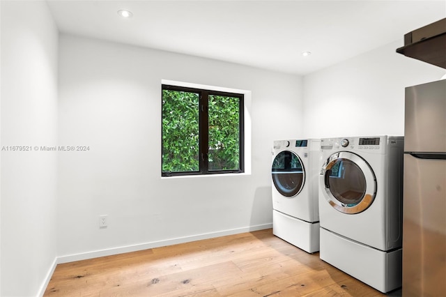 clothes washing area with separate washer and dryer and light hardwood / wood-style flooring