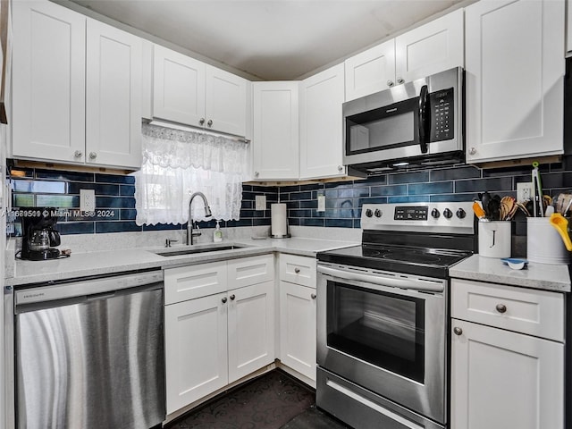 kitchen featuring appliances with stainless steel finishes, white cabinetry, sink, and backsplash