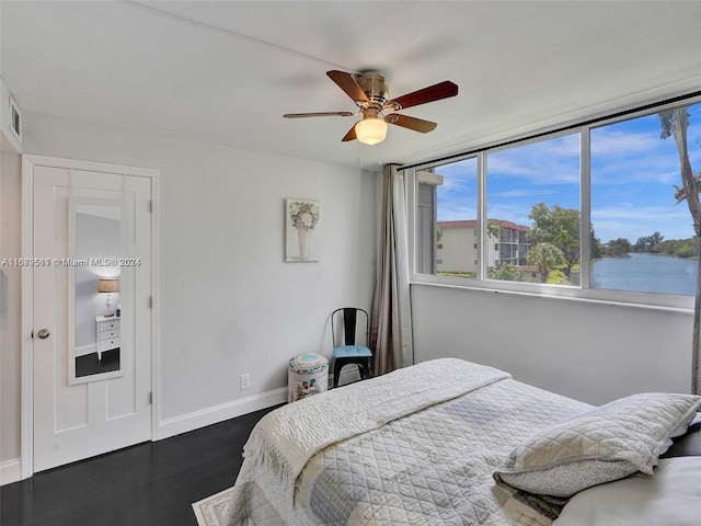 bedroom with a water view, ceiling fan, and dark hardwood / wood-style floors