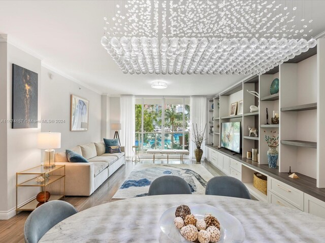 living room with light hardwood / wood-style floors, ornamental molding, and a chandelier