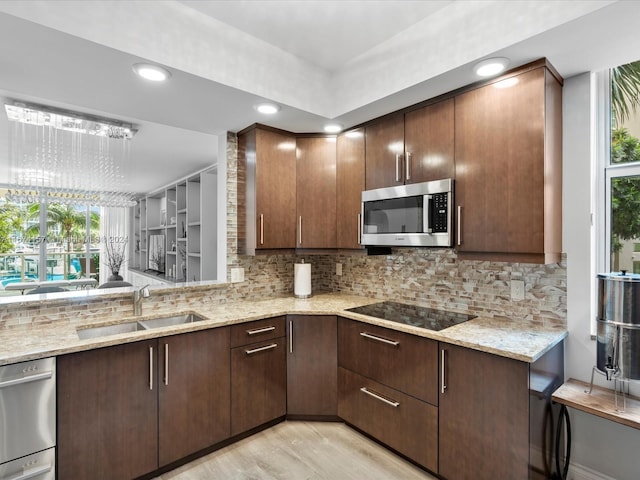 kitchen with decorative backsplash, sink, appliances with stainless steel finishes, light stone counters, and light hardwood / wood-style floors