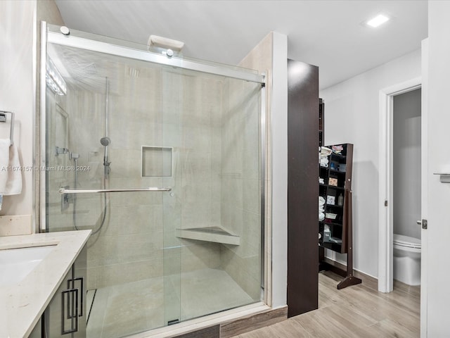 bathroom with vanity, a shower with shower door, hardwood / wood-style flooring, and toilet