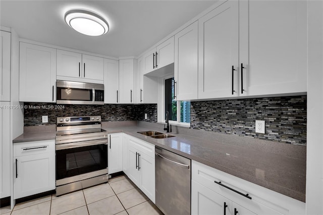 kitchen with light tile patterned floors, stainless steel appliances, sink, and white cabinets