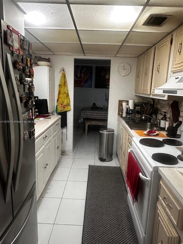 kitchen with light tile patterned floors, backsplash, white electric range oven, stainless steel refrigerator, and a drop ceiling