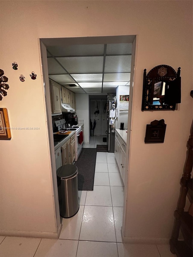 kitchen featuring white range with electric cooktop, a paneled ceiling, stainless steel refrigerator, and light tile patterned floors