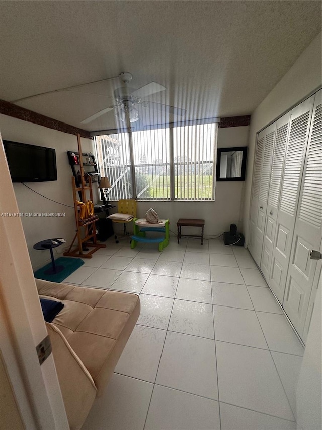 interior space with ceiling fan, a textured ceiling, and tile patterned flooring