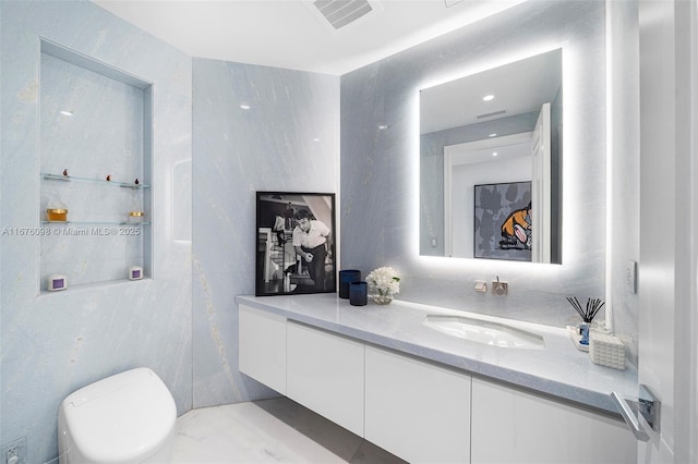 bathroom featuring toilet, vanity, and visible vents