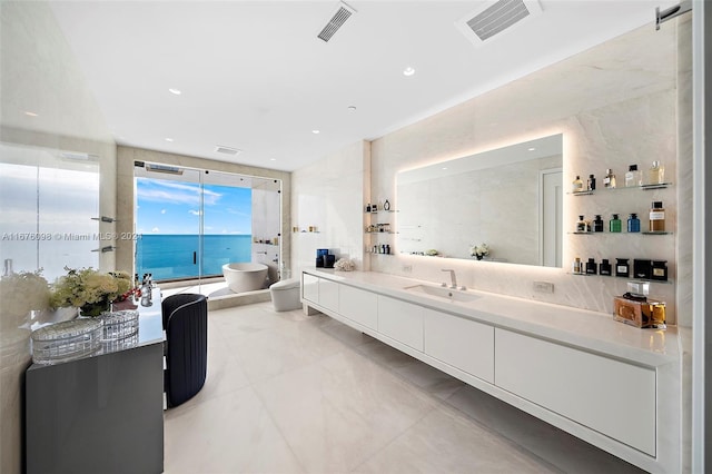 bathroom with tile walls, a bidet, vanity, toilet, and a water view