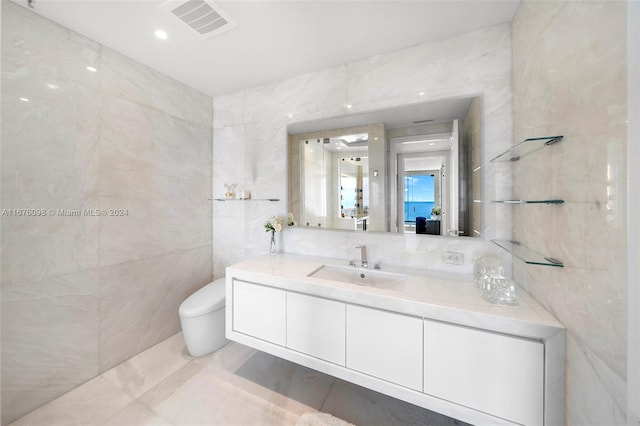 bathroom with tile walls, vanity, and toilet