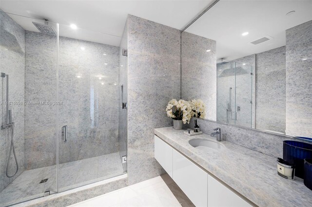 bathroom featuring vanity, an enclosed shower, and tile walls