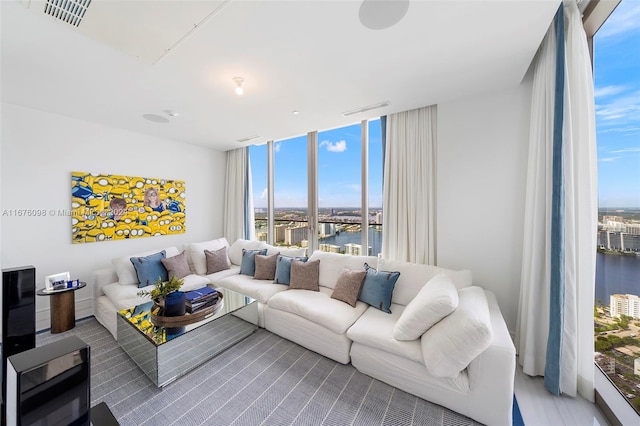 living room featuring wood-type flooring, a water view, and floor to ceiling windows