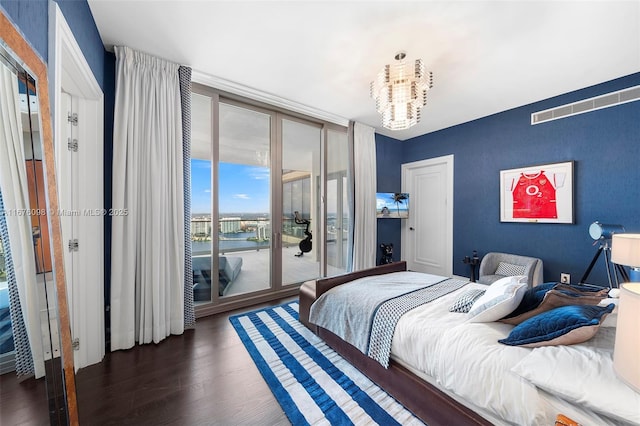 bedroom featuring access to outside, wood finished floors, visible vents, and a notable chandelier