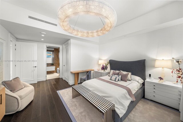 bedroom featuring dark hardwood / wood-style floors, a chandelier, and a tray ceiling