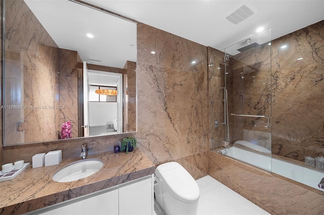 full bathroom featuring tile walls, vanity, tiled shower / bath, and toilet