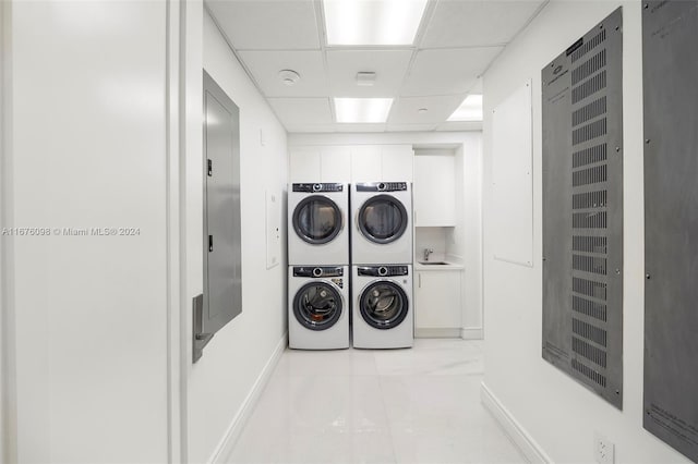 clothes washing area with cabinets, stacked washer and dryer, and washer and clothes dryer