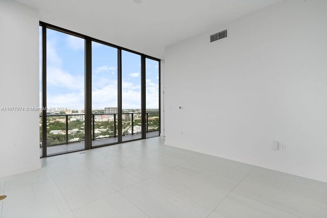 tiled spare room with floor to ceiling windows and a wealth of natural light