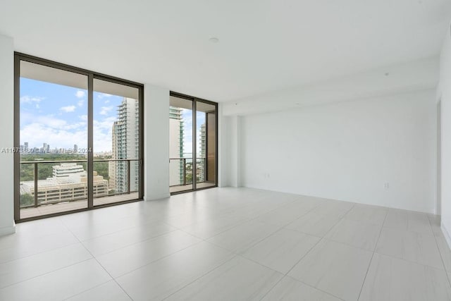 tiled empty room featuring a healthy amount of sunlight and floor to ceiling windows