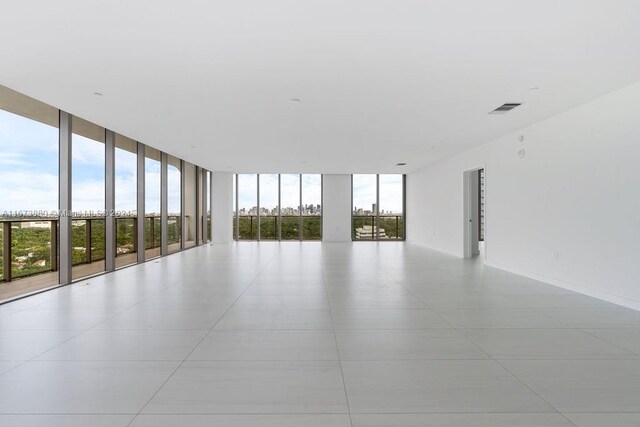 spare room featuring a wall of windows, a wealth of natural light, and light tile patterned flooring