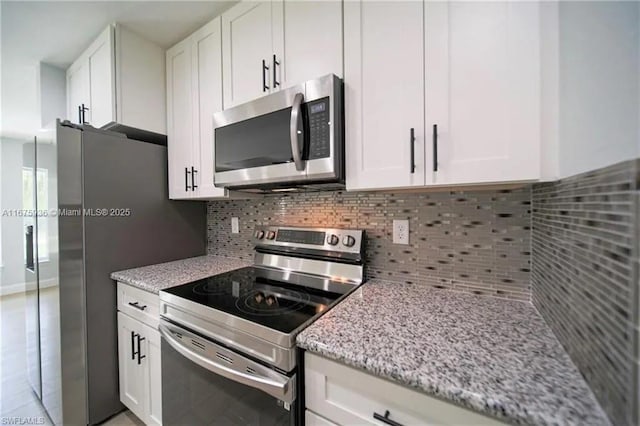 kitchen featuring white cabinets, decorative backsplash, light stone counters, and stainless steel appliances