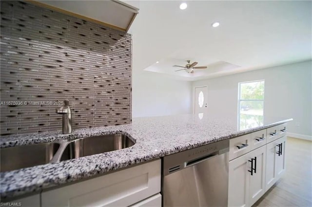 kitchen featuring light stone countertops, tasteful backsplash, stainless steel dishwasher, sink, and white cabinetry