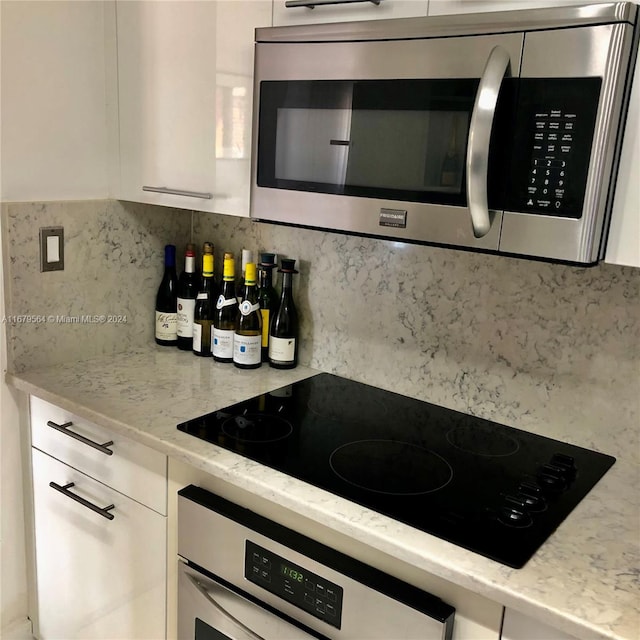 kitchen featuring white cabinetry, light stone counters, tasteful backsplash, and appliances with stainless steel finishes