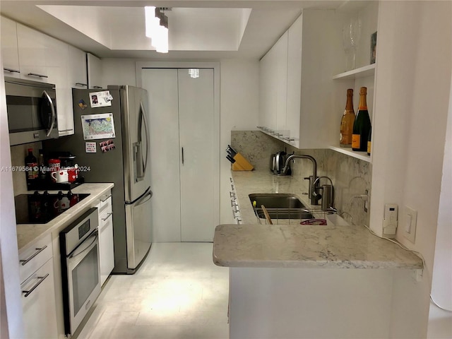 kitchen with white cabinets, a raised ceiling, backsplash, sink, and stainless steel appliances