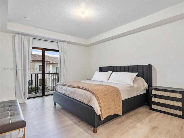 bedroom featuring light hardwood / wood-style flooring, a textured ceiling, and access to outside