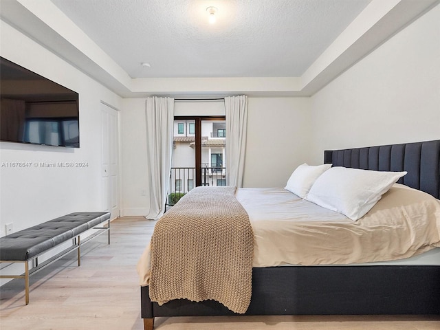 bedroom with a textured ceiling, access to exterior, and light wood-type flooring