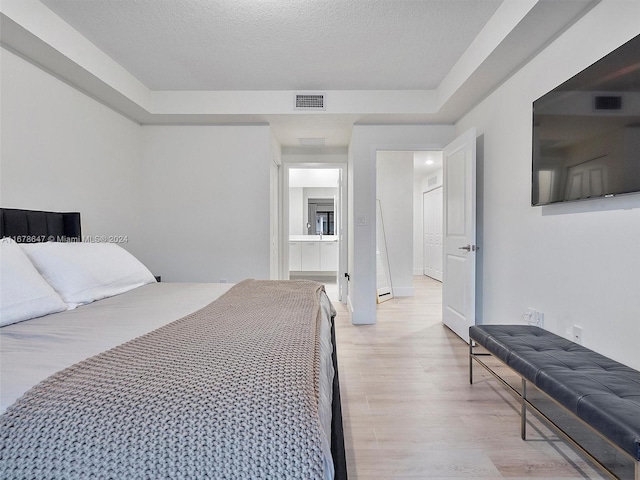 bedroom with a textured ceiling and light hardwood / wood-style flooring