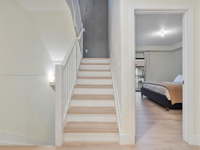 stairs featuring a textured ceiling and wood-type flooring