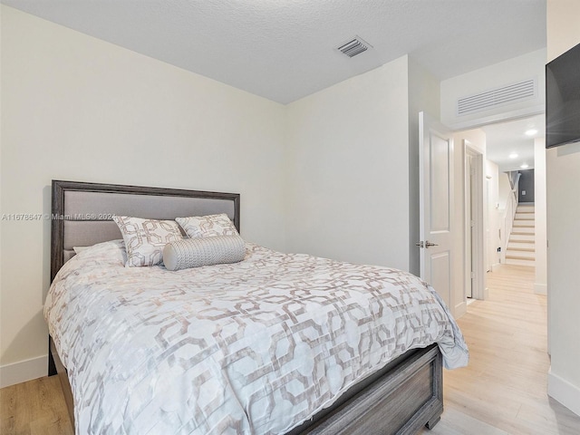 bedroom with light hardwood / wood-style floors and a textured ceiling