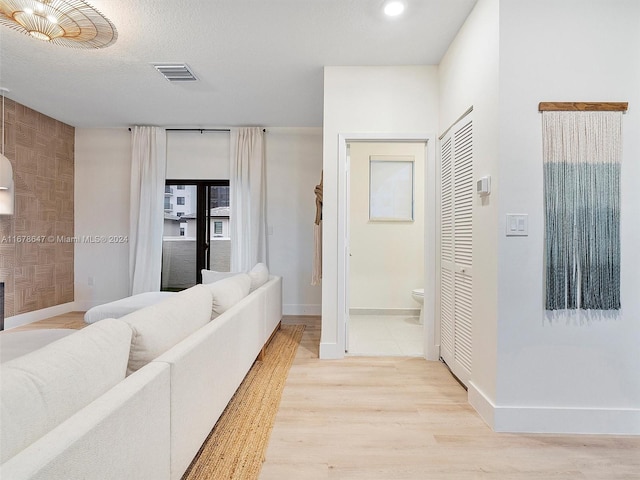 corridor with a textured ceiling and light hardwood / wood-style flooring