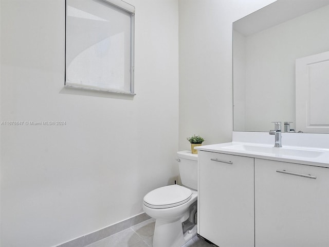 bathroom with toilet, vanity, and tile patterned flooring