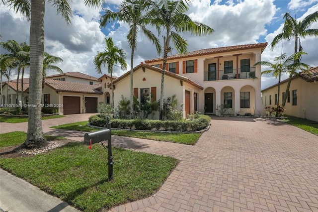 mediterranean / spanish-style home with a front yard, a balcony, and a garage