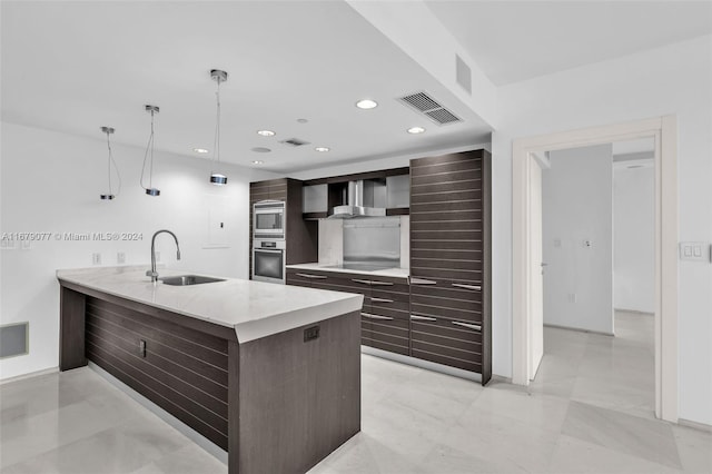 kitchen featuring pendant lighting, sink, appliances with stainless steel finishes, dark brown cabinets, and kitchen peninsula