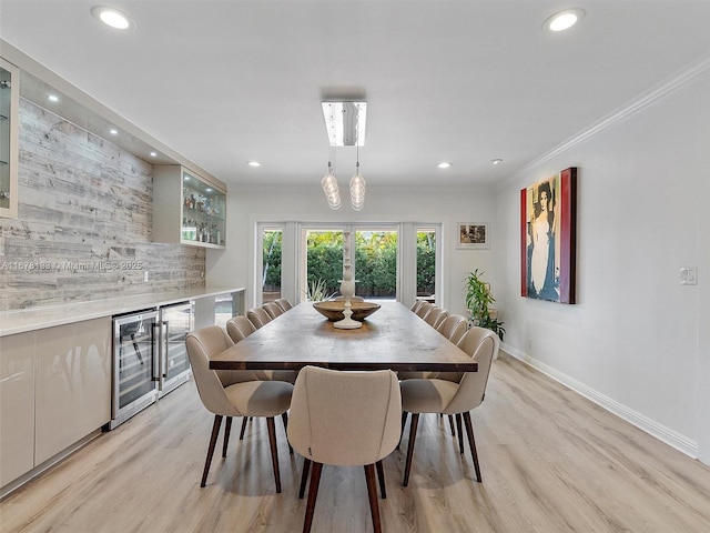 dining room featuring bar, wine cooler, ornamental molding, and light hardwood / wood-style floors