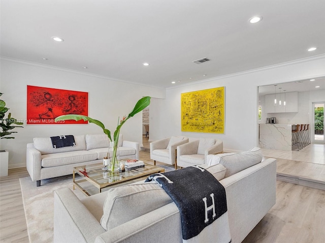 living area with crown molding, recessed lighting, visible vents, and light wood-type flooring