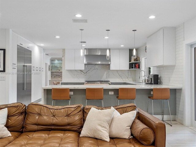 kitchen featuring gray cabinetry, light stone counters, pendant lighting, and built in fridge