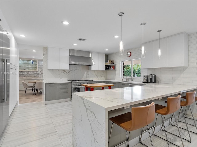 kitchen with visible vents, a peninsula, modern cabinets, and wall chimney exhaust hood