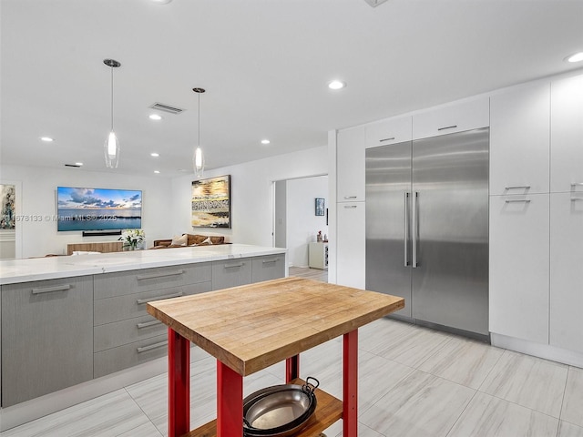 kitchen with visible vents, gray cabinetry, stainless steel built in fridge, hanging light fixtures, and modern cabinets