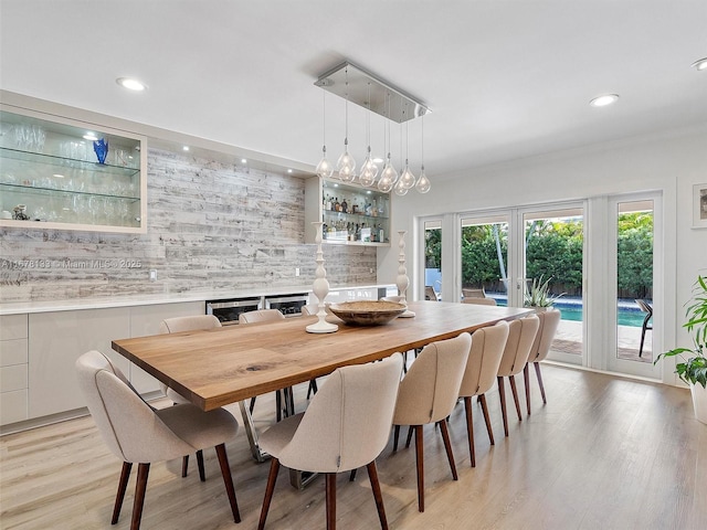 dining room featuring a bar, light wood-style flooring, and recessed lighting